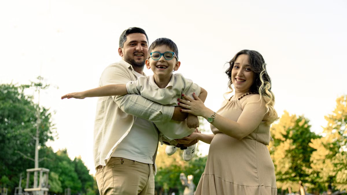 A joyful family with a child and pregnant mother enjoying an outdoor day in the park.